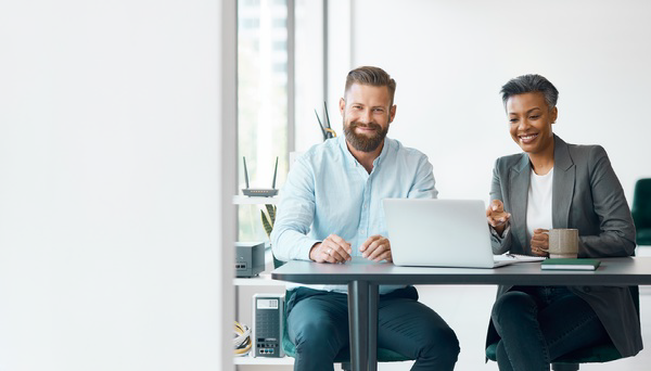 Two business professionals reviewing a laptop together in a bright office